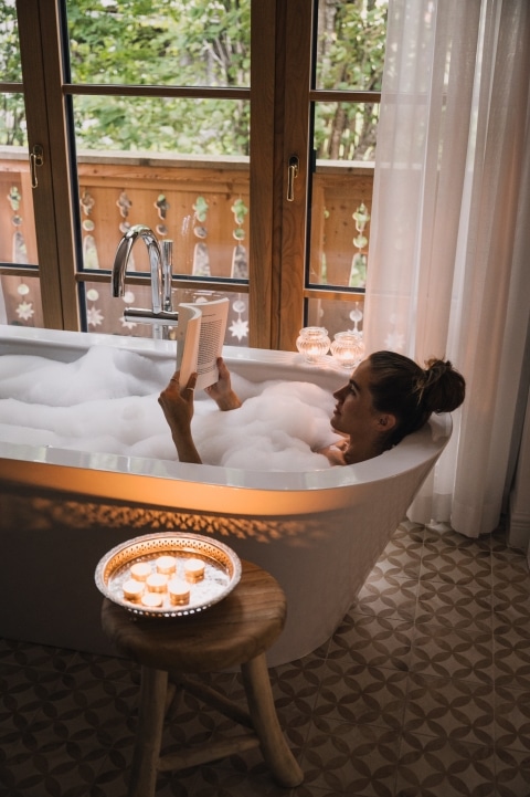 Lady lies in the bathtub and reads a book